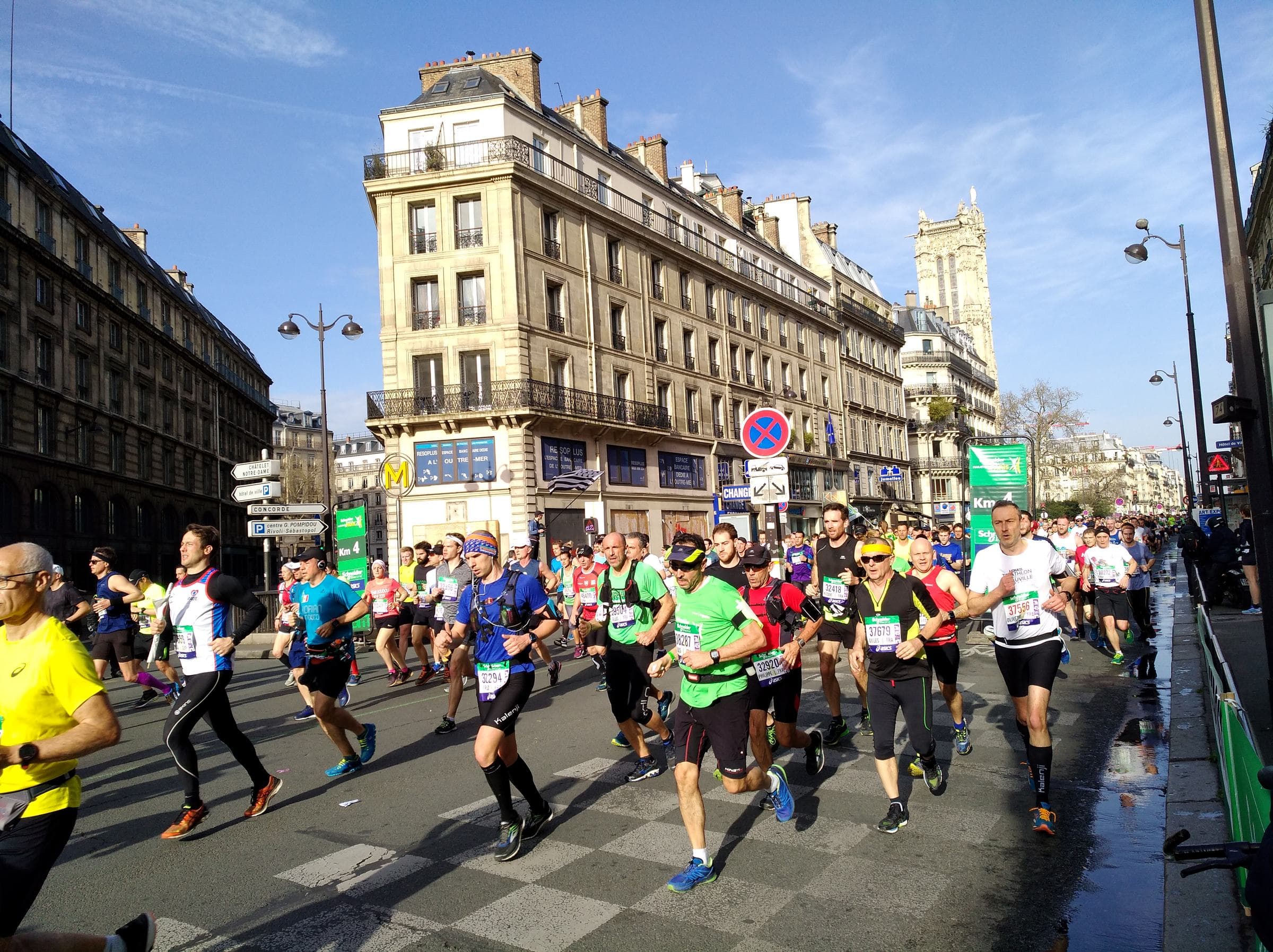 Marathon de Paris runners passing the four-kilometre mark on Rue de Rivoli, the Tour Saint-Jacques behind them